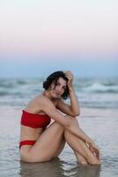 sexy retour de une magnifique femme dans rouge bikini sur mer Contexte photo