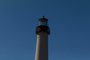 cette est le Haut image de cape mai point phare. le rouge métal Haut des stands en dehors contre le blanc brique de le la tour. photo