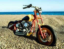 une jouet moto est assis sur le le sable près le océan photo