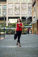 magnifique femme Aller à travail avec café en marchant près Bureau bâtiment. photo