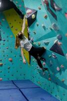 Jeune femme escalade en haut sur entraine toi mur dans Gym photo