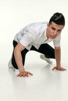 beau, jeune, branché homme est séance sur le sol dans studio photo