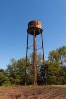 une magnifique l'eau la tour est ensemble autour un abandonné zone. cette rouillé métal structure des stands grand contre une bleu ciel. photo