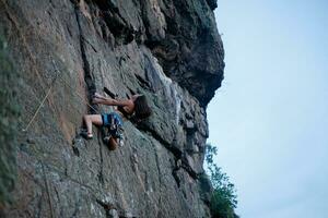 une fille grimpe une rock. femme engagé dans extrême sport. photo