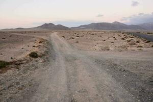 une saleté route dans le désert avec montagnes dans le Contexte photo