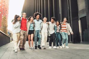 Multi-éthnique groupe de Jeune content copains en marchant vers le bas le rue en portant chaque autre affectueusement. photo