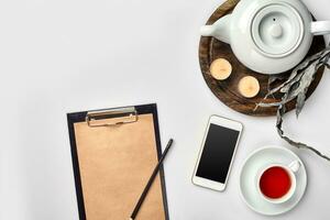 carnet avec artisanat papier, mobile téléphone, noir thé, des lunettes sur blanc Contexte avec copie espace. photo