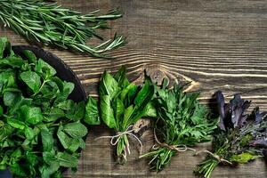 variété de Frais biologique herbes sur en bois Contexte. fraîchement récolté herbes comprenant basilic, Roquette. Haut voir. copie espace. photo