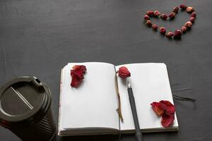 Haut vue de un vide carnet de notes, album accessoires et une tasse de café sur une noir Contexte. photo