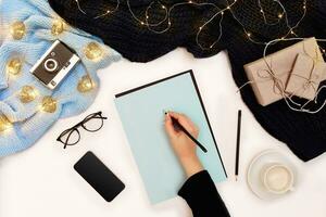 femme mains dans une tricoté noir chandail, en portant stylo près le Vide papier, vue de le Haut photo