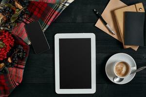 numérique tablette ordinateur avec carnet et tasse de café sur vieux en bois bureau. Facile espace de travail ou café Pause avec la toile surfant. photo