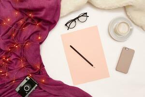 une tasse de café, intelligent, rose papier avec Nouveau ans buts. écharpe et Noël lumières sur blanc Contexte. photo