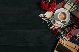 au dessus vue de intelligent téléphone avec carnet et tasse de latté café sur noir en bois Contexte. photo