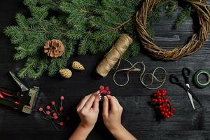 fabricant de Noël décor avec leur posséder mains. Noël couronne pour le vacances. le Nouveau année fête. Haut vue photo