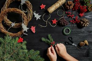 fabricant de Noël décor avec leur posséder mains. Noël couronne pour le vacances. le Nouveau année fête. Haut vue photo