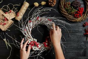 fabricant de Noël décor avec leur posséder mains. Noël couronne pour le vacances. le Nouveau année fête. Haut vue photo