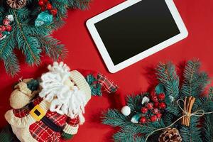 Noël décorations et blanc tablette avec noir écran sur chaud rouge Contexte. Noël et Nouveau année thème. endroit pour votre texte, vœux, logo. moquer en haut. photo