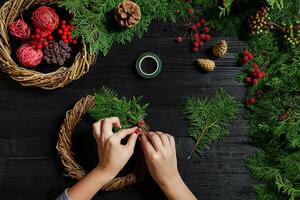 fabricant de Noël décor avec leur posséder mains. Noël couronne pour le vacances. le Nouveau année fête. Haut vue photo