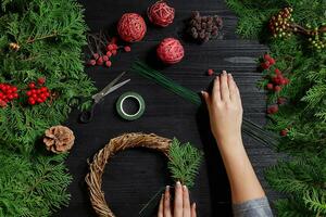 fabricant de Noël décor avec leur posséder mains. Noël couronne pour le vacances. le Nouveau année fête. Haut vue photo