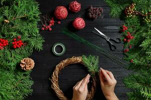 fabricant de Noël décor avec leur posséder mains. Noël couronne pour le vacances. le Nouveau année fête. Haut vue photo