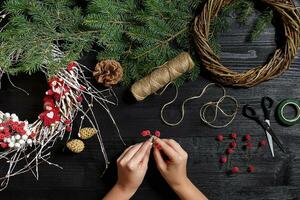 fabricant de Noël décor avec leur posséder mains. Noël couronne pour le vacances. le Nouveau année fête. Haut vue photo