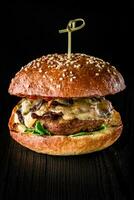 fromage Burger avec grillé Viande, fromage, tomate sur foncé en bois surface. idéal pour publicité. fermer photo