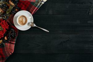 blanc tasse de le café et ancien écharpe sur noir en bois Contexte photo