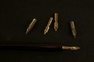 une stylo avec une or plume et quatre autre or plumes photo