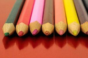 une rangée de coloré des crayons sur une rouge surface photo