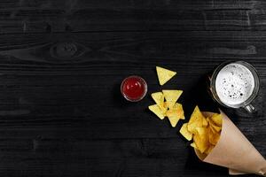 Haut vue de tortilla frites avec sauce, verre de Bière sur noir en bois Contexte photo