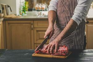 homme coupes de Frais pièce de Viande sur une en bois Coupe planche dans le Accueil cuisine photo