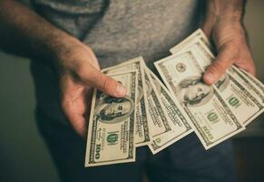 une homme détient dollars dans le sien mains photo