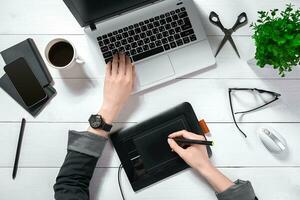 Haut vue de femme mains dactylographie sur portable clavier mis sur blanc Bureau bureau avec café Coupe. photo