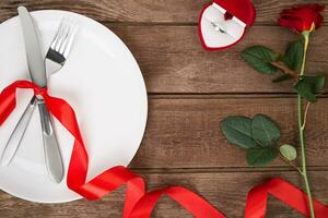 valentines journée table réglage avec plaque, fourchette, couteau, anneau, ruban et Rose. Contexte photo