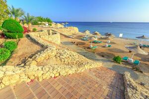 plage avec plate-forme chaises et parasol pendant le coucher du soleil photo