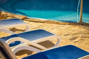 fermer nombreuses de Soleil chaises longues par une magnifique nager bassin. photo