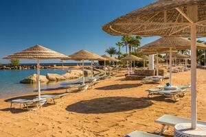 paille parapluies et transats sur le magnifique tropical plage. photo