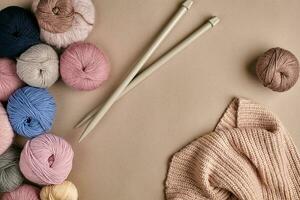 ensemble de coloré la laine fil et tricot sur tricot aiguilles sur beige Contexte. Haut vue photo