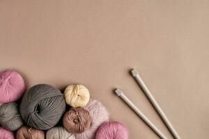 une groupe de coloré des balles de fil et tricot aiguilles sur une beige Contexte photo