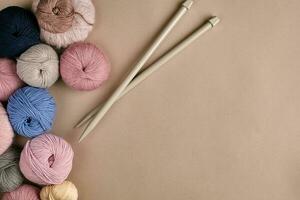 une groupe de coloré des balles de fil et tricot aiguilles sur une beige Contexte photo