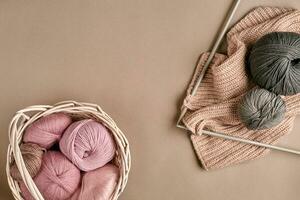 des balles de mérinos la laine fil, tricot sur tricot aiguilles sur une beige surface. Haut vue photo