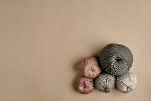 gris et marron tricot la laine et tricot aiguilles sur beige Contexte. Haut voir. copie espace photo