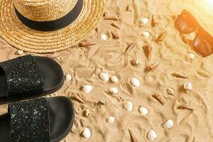 été tenue de plage, retourner flops, chapeau, des lunettes de soleil et coquillages sur le sable plage. photo