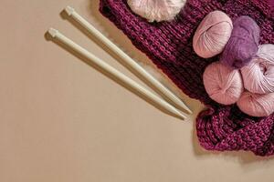 une groupe de coloré des balles de fil et tricot aiguilles sur une beige Contexte photo