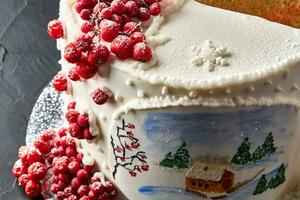 hiver gâteau couvert avec blanc glaçage, avec peint maison dans le forêt, des arbres et rouge sorbier des oiseleurs. photo