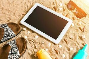 été tongs, tablette, lunettes de soleil et coquillage sur sable. avec endroit pour votre texte. Haut vue photo