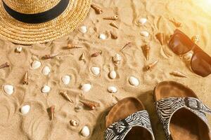 été tenue de plage, retourner flops, chapeau, des lunettes de soleil et coquillages sur le sable plage. photo