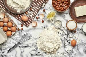 fermer tir. Haut vue de une cuisson Ingrédients et ustensiles de cuisine sur le marbre table Contexte. photo