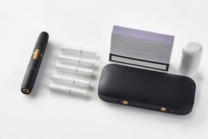 Nouveau génération noir électronique cigarette batterie, nettoyeur, pack avec violet côté, cinq bâtons chauffants isolé sur blanche. chauffage le tabac système. proche en haut photo