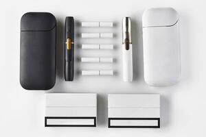 Nouveau génération, noir et blanc deux électronique cigarettes et batteries, cinq des bâtons chauffants, packs isolé sur blanche. chauffage le tabac système. proche en haut photo